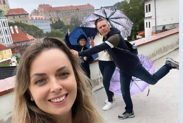 Семья с зонтиками на террасе с видом на Чески-Крумлов